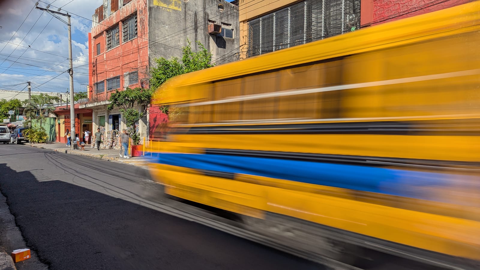 A yellow bus moving through San Salvador street traffic