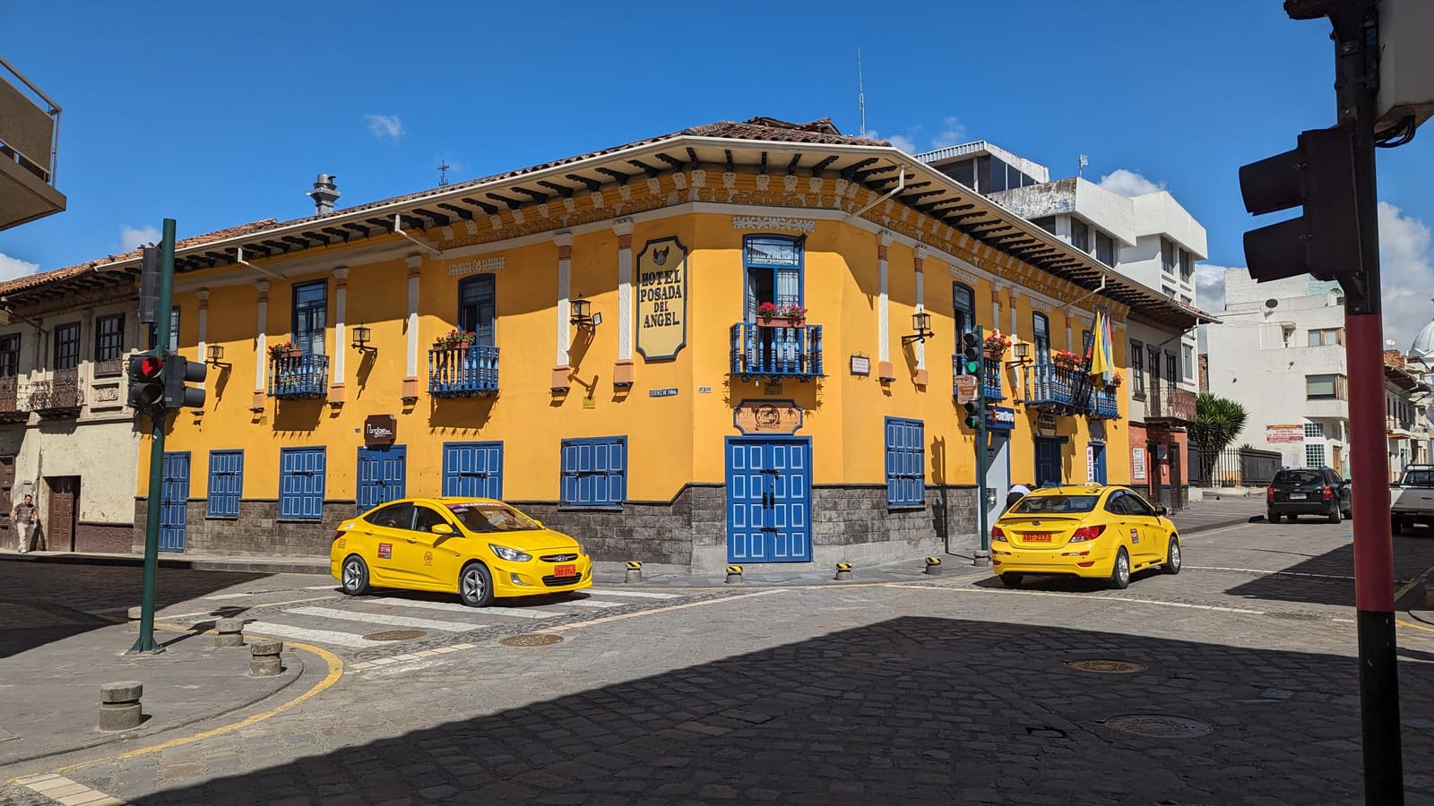Yellow colonial corner building with taxis in Cuenca