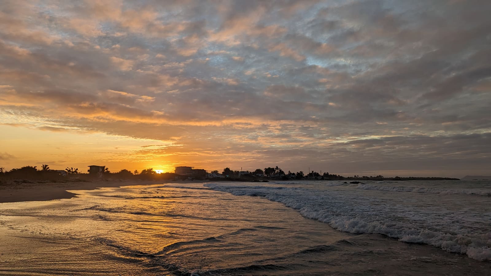 Orange sunset over the ocean at Puerto Villamil beach