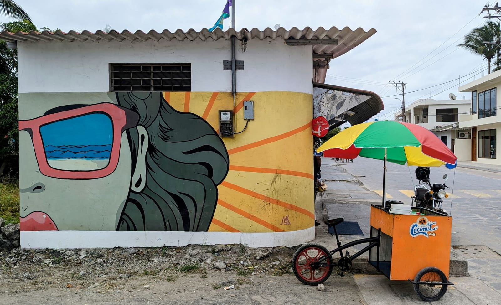 Painted mural and umbrella cart on a sandy street in Puerto Villamil