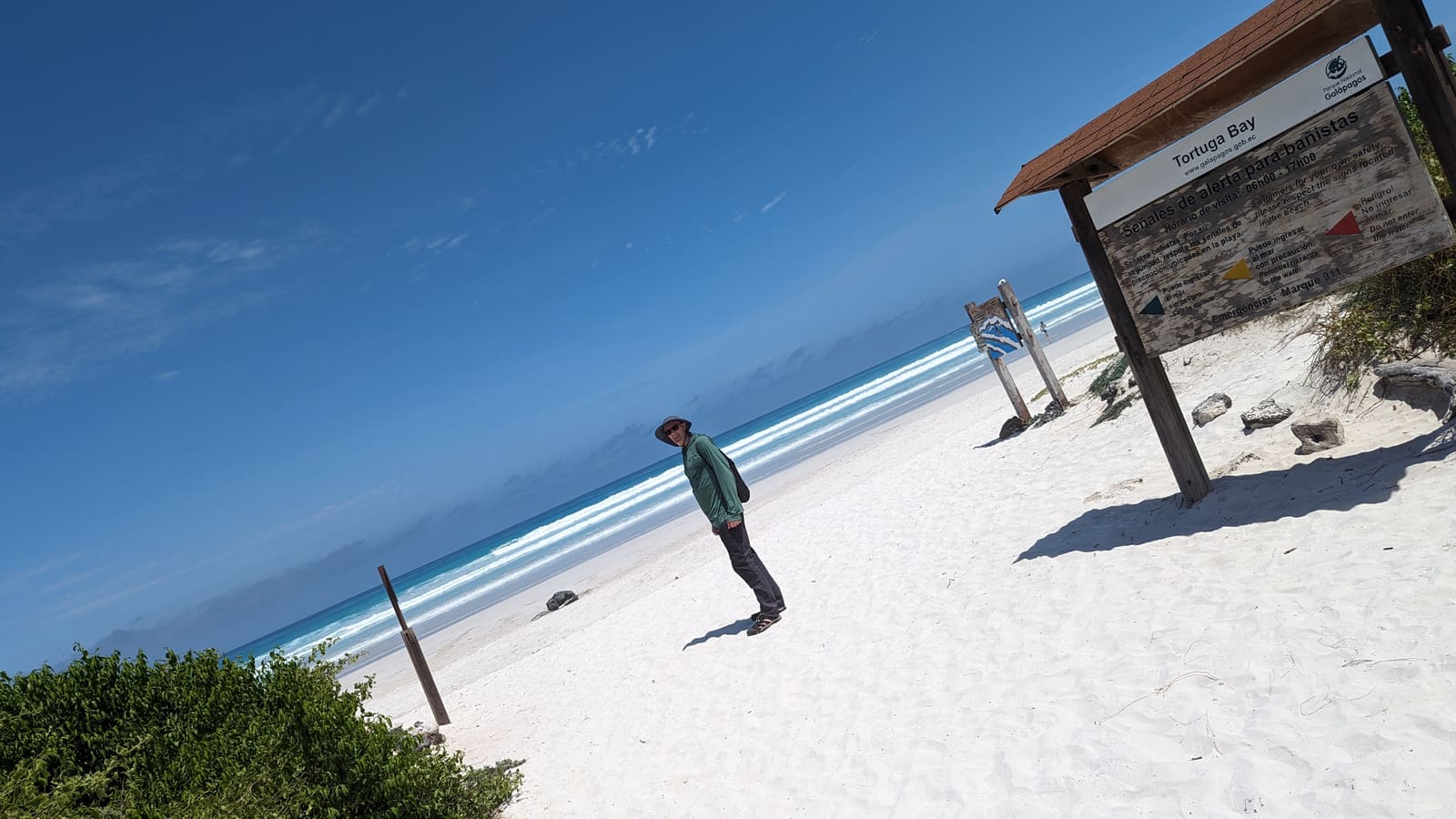 A lone traveler standing on the wide white sand of Tortuga Bay, Santa Cruz