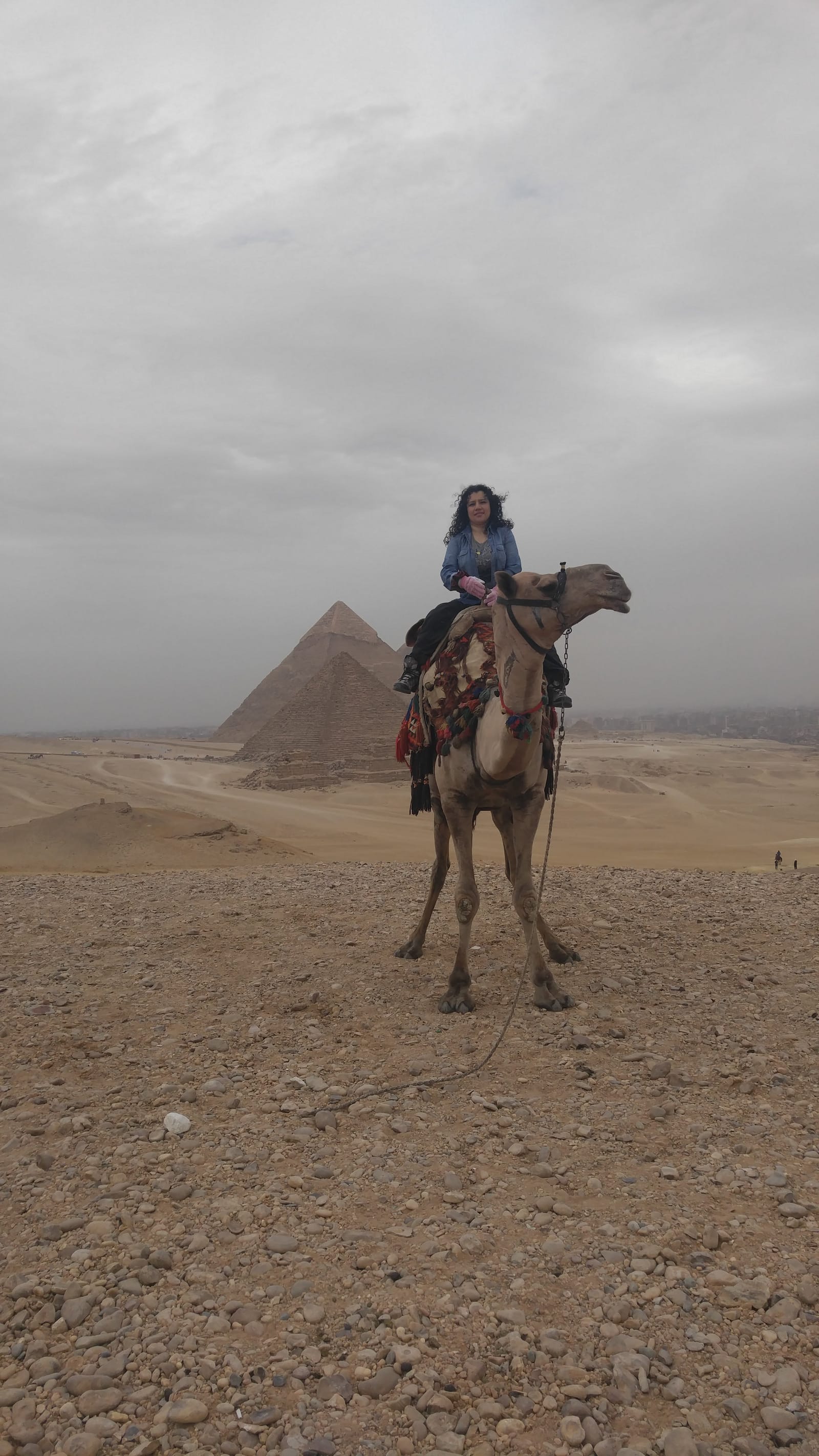 A couple riding camels with the pyramids in the background