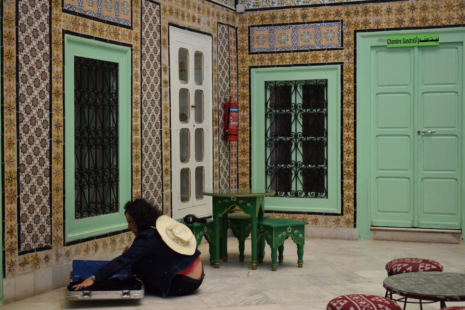 A visitor seated in a green-and-gold tiled traditional Tunisian room